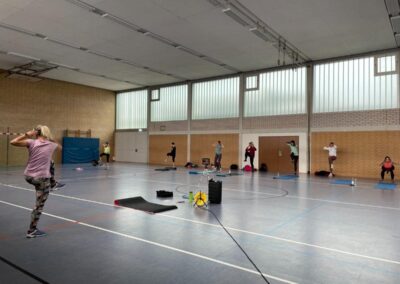 Turnhalle mit Personen beim Body Fit im Stehen