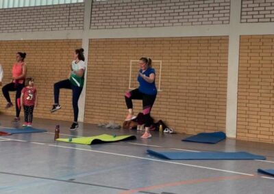 Turnhalle mit Personen beim Body Fit im Stehen