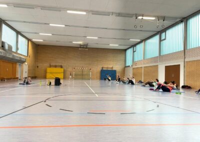 Turnhalle mit Personen beim Body Fit am Boden