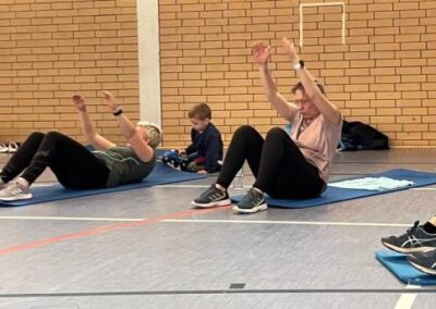 Turnhalle mit Personen beim Body Fit am Boden