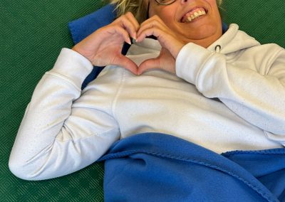 ÜL Kerstin liegt auf Boden und zeigt ein Herz