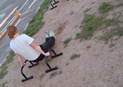 3 Leute üben den L-Sit und Push ups an Dip-Stangen